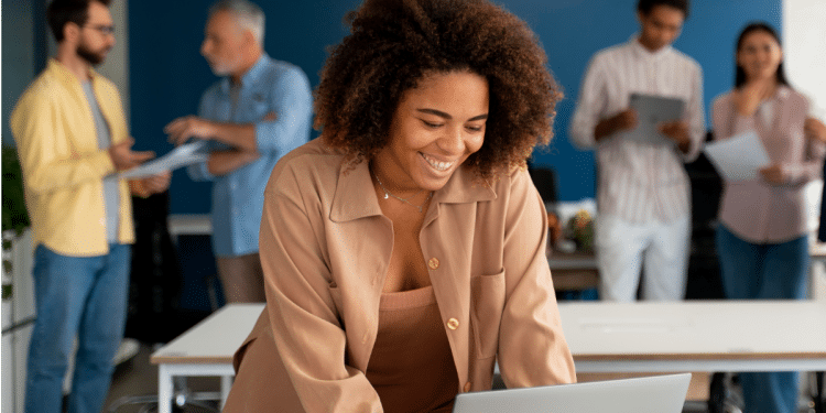 Jovem sorrindo trabalhando em equipe em escritório moderno.