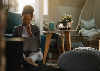 Pessoa em ambiente de trabalho remoto em casa usando notebook, simbolizando efeitos do home office sobre a saúde mental e o aumento do isolamento social.