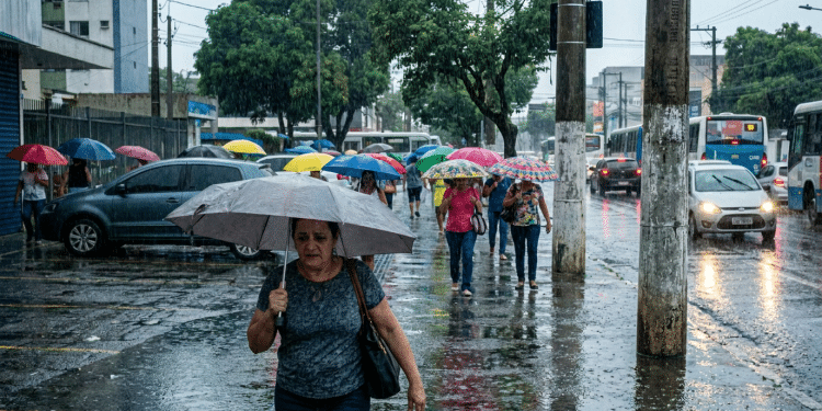 Pedestres atravessam avenida movimentada sob forte chuva em cidade brasileira.