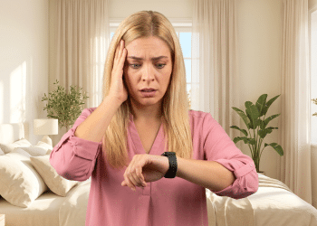 Mulher preocupada olha relógio smartwatch em quarto claro.