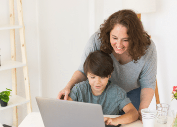 Mães ensinando o filho a mexer no notebook.