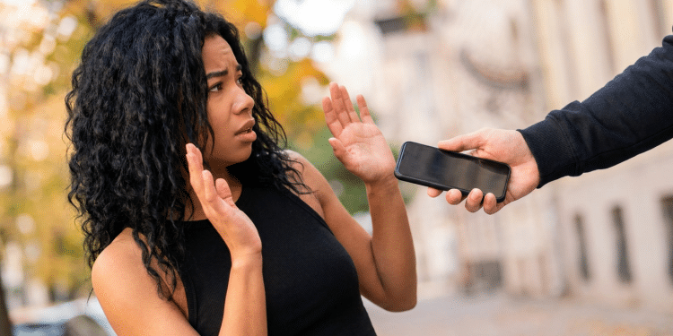Mulher assustada enquanto homem rouba seu celular.