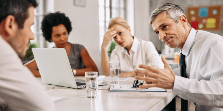 Equipe discute soluções em reunião corporativa com tensão aparente.