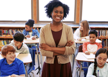 Professora sorridente com estudantes em sala de aula.
