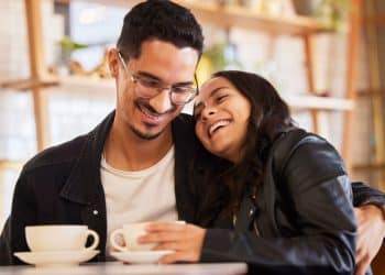 Casal sorridente aproveita momento juntos em cafeteria.