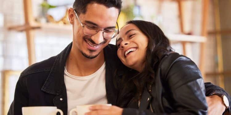 Casal sorridente aproveita momento juntos em cafeteria.