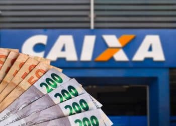 Leque de notas de R$ 50 e R$ 200 em frente a uma agência da Caixa, em imagem que ilustra o pagamento do Abono Salarial PIS/Pasep de 2026