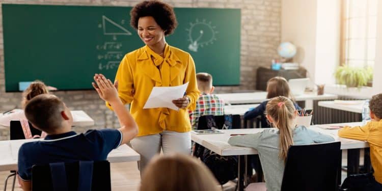 Imagem ilustrativa de uma professora em sala de aula com alunos, tema da matéria sobre como abreviar a palavra professora.
