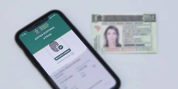 Celular exibindo o aplicativo e-Título com a mensagem "Biometria coletada" ao lado de uma carteira de identidade