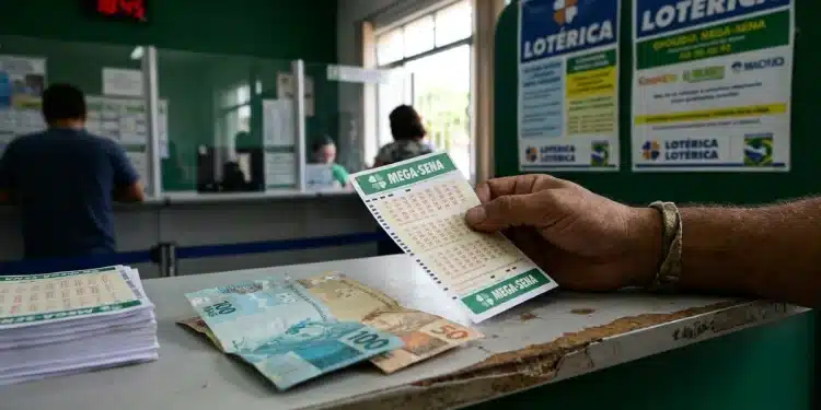 Apostador segura volante da Mega-Sena em casa lotérica, com cédulas de real sobre o balcão, em dia de apostas para prêmio de R$ 16 milhões.