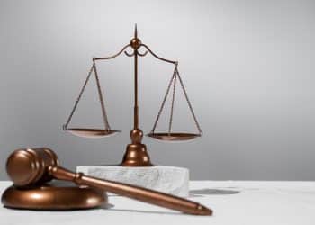 Balança da justiça e martelo de juiz em cobre sobre superfície clara, simbolizando as áreas de atuação para formados em direito.