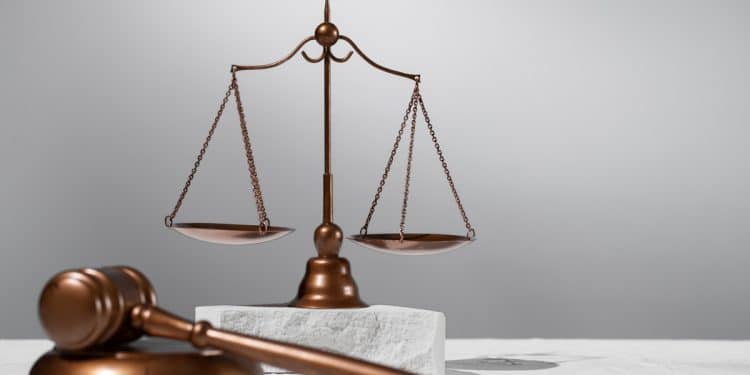 Balança da justiça e martelo de juiz em cobre sobre superfície clara, simbolizando as áreas de atuação para formados em direito.