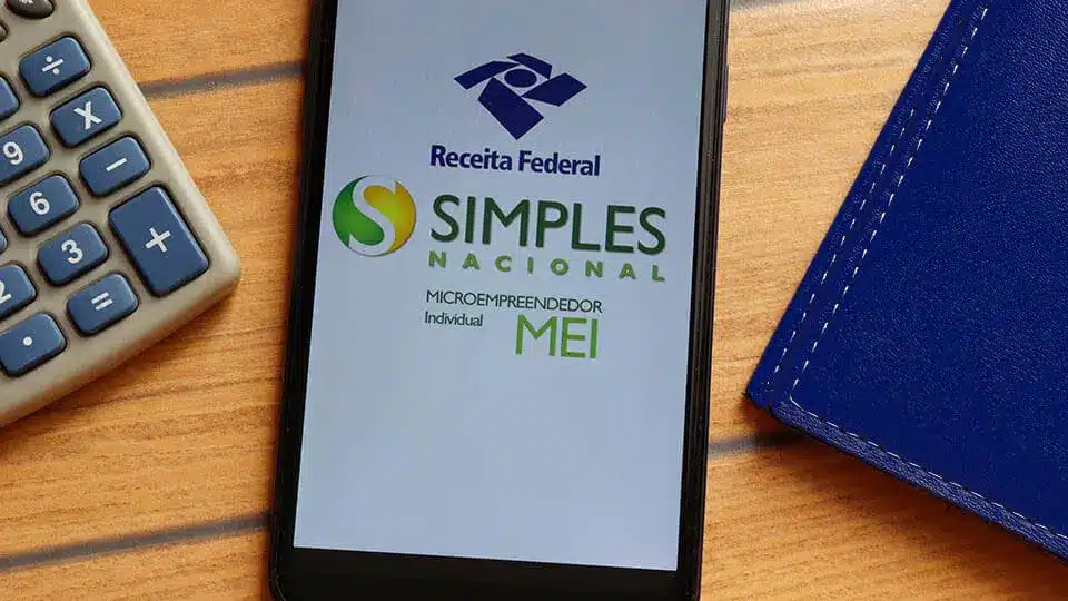 Celular mostra o Simples Nacional ao lado de calculadora, simbolizando o limite de faturamento do MEI
