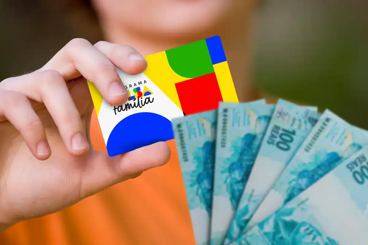 Mão segurando cartão do Bolsa Família e dinheiro em espécie durante pagamento do benefício.