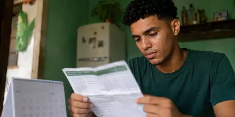 Jovem estudante conferindo folha com calendário do Pé-de-Meia 2027