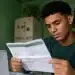 Jovem estudante conferindo folha com calendário do Pé-de-Meia 2027