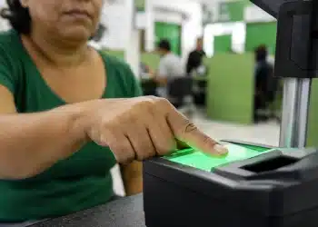 Pessoa realizando coleta de impressão digital em estação de biometria para emissão da nova Carteira de Identidade.