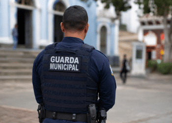 Guarda municipal visto de costas usando uniforme em área urbana.