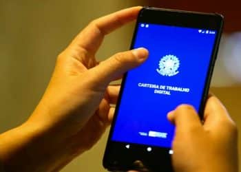 Mãos segurando um celular com o aplicativo Carteira de Trabalho Digital aberto, ferramenta usada para consultar o Abono Salarial do PIS/Pasep em 2026