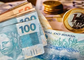 Cédulas de R$ 50 e R$ 100 e moeda de R$ 1 sobre notas do Banco Central, representando o dinheiro esquecido que pode ser resgatado no Sistema de Valores a Receber.