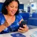 Mulher consultando no celular se tem valores do PIS/PASEP de 1971 a 1988 para sacar