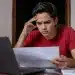 Jovem estudante brasileiro concentrado em notebook, em ambiente doméstico simples, com expressão de atenção e preocupação, representando a inscrição no Enem 2026 antes do prazo final.