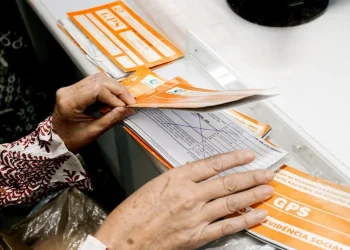 Pessoa organiza documentos do INSS para verificar contribuições previdenciárias em atraso.