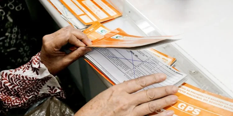 Pessoa organiza documentos do INSS para verificar contribuições previdenciárias em atraso.
