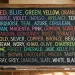 Quadro escolar com nomes de cores em inglês escritos em letras coloridas, representando o estudo de vocabulário.