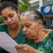 Jovem acompanhando idosa na leitura de documento sobre requisitos para receber o BPC