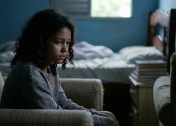 Criança sentada sozinha em um ambiente escuro, representando sinais de depressão infantil que podem passar despercebidos pelos pais.