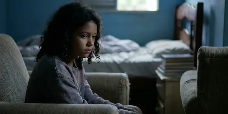 Criança sentada sozinha em um ambiente escuro, representando sinais de depressão infantil que podem passar despercebidos pelos pais.