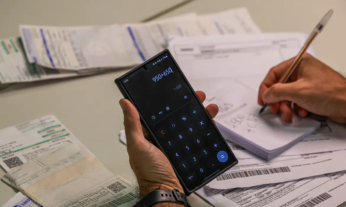 Pessoa calcula contas atrasadas, situação que o Novo Desenrola busca resolver com a renegociação de dívidas de famílias e empresas