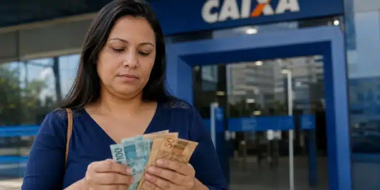 Mulher conferindo cédulas de dinheiro em frente à agência da Caixa, com dúvidas sobre a elegibilidade ao PIS/Pasep para quem recebe R$ 3.000.