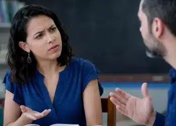 Duas pessoas em debate em sala de aula, representando a dúvida entre usar “degladiar” ou “digladiar”.
