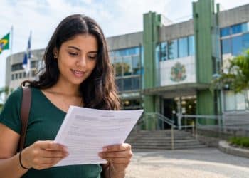Mulher lê documento em frente a prédio público, representando as inscrições abertas do concurso da Câmara de Mauá