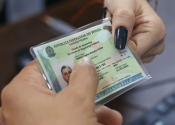 Mãos seguram a nova Carteira de Identidade Nacional plastificada com brasão da República e dados do portador.