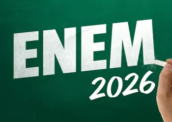 Mão escrevendo “ENEM 2026” em um quadro verde, ilustrando o prazo para pagamento da taxa de inscrição até 10 de junho.