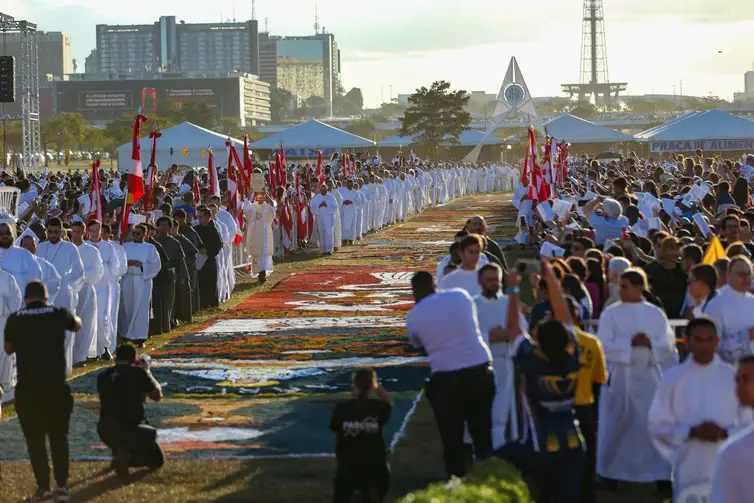 Multidão de fiéis e religiosos acompanha celebração de Corpus Christi ao redor de extenso tapete decorado ao ar livre