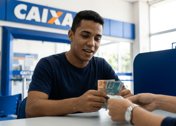 ovem recebe cédulas de real no caixa de uma agência da Caixa