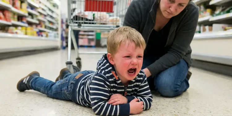 Criança chorando no supermercado com mãe tentando acalmá-la.