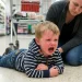 Criança chorando no supermercado com mãe tentando acalmá-la.