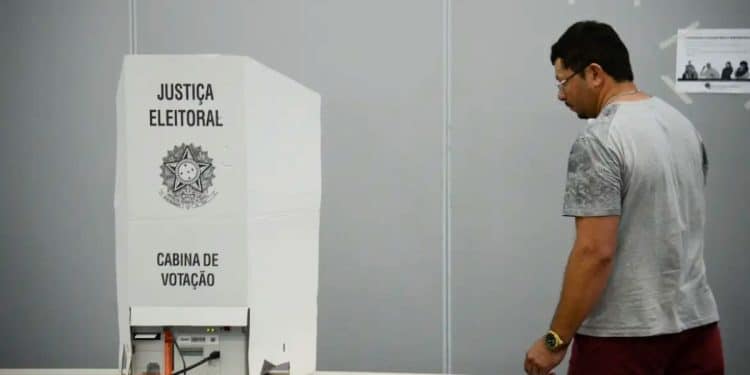 Eleitor diante de cabine de votação da Justiça Eleitoral em seção eleitoral