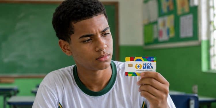 Estudante observa o cartão do Pé-de-Meia, que dá acesso ao Incentivo-Conclusão.