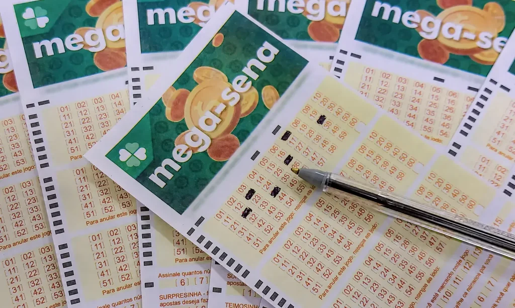 Volantes da Mega-Sena com caneta sobre apostas preenchidas, representando as opções para registrar jogos em lotéricas e canais online.