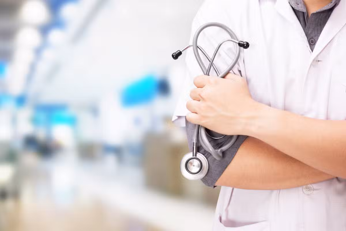 Médico de jaleco e braços cruzados segura um estetoscópio, representando os candidatos à residência no Enare 2026/2027