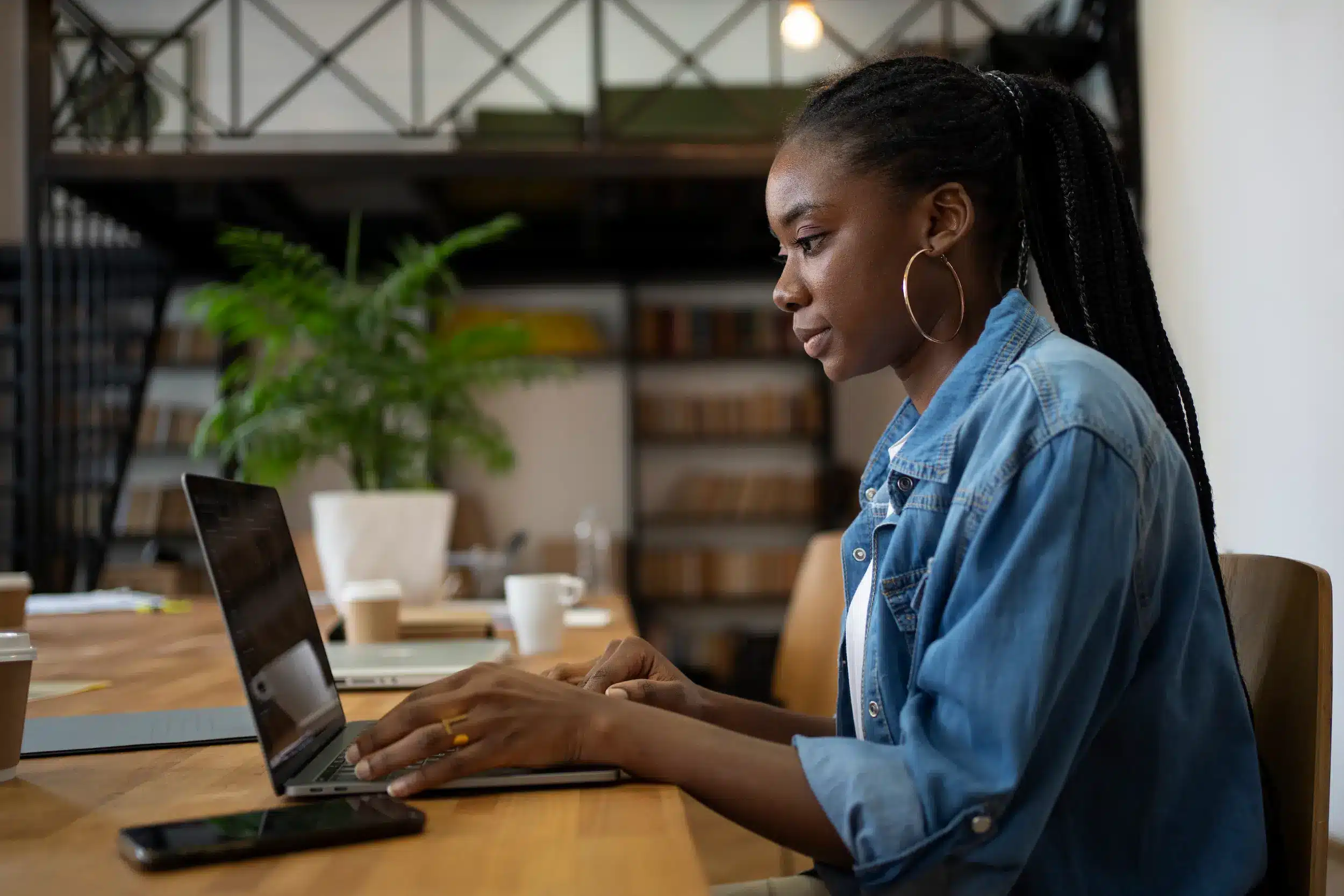 Mulher negra usando notebook em ambiente de trabalho, em referência às barreiras salariais enfrentadas no mercado.