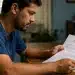 Homem analisando um termo de rescisão com notas de dinheiro sobre a mesa, representando a multa de 40% em caso de demissão sem justa causa.