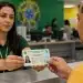 Servidora pública entrega nova Carteira de Identidade Nacional durante atendimento em órgão oficial, sem a exigência do CPF para emissão.