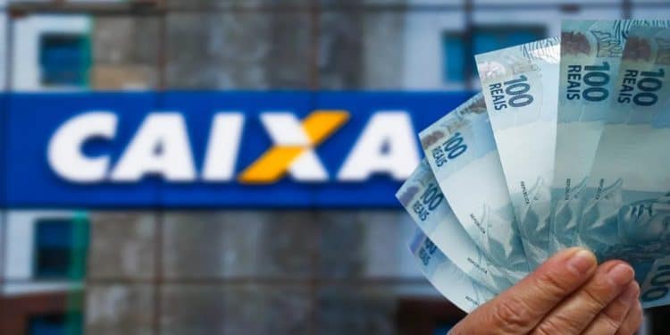 Notas de cem reais em frente à fachada da Caixa, banco que paga o Abono Salarial e o ressarcimento do PIS/Pasep.